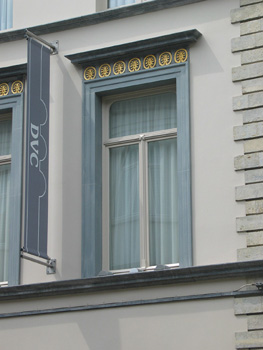 gouden motieven boven raam en langwerpige grijze vlag